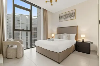 a large bedroom with a large bed and a chair at FIRST CLASS 1BR Cozy Luxe Escape in Dubai