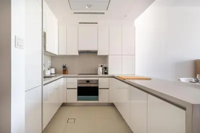 a white kitchen with white cabinets and appliances at Serene 1BR Retreat with Pool & Gym by Safa Park in Dubai