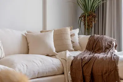 a white couch with pillows and a potted plant at Serene 1BR Retreat with Pool & Gym by Safa Park in Dubai
