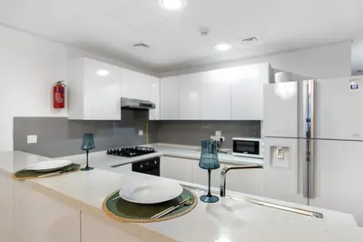 a kitchen with white cabinets and a refrigerator at Stylish 1BR Canal View & 12 min to Downtown in Dubai