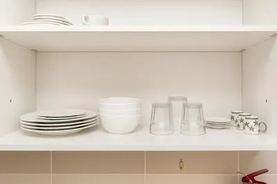 a white kitchen shelf with plates and dishes on it at Spacious 1BR Apartment Imperial Residence B JVT in Dubai
