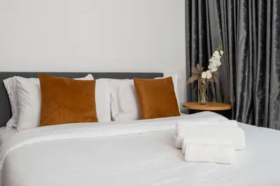 a white bed with pillows and a vase of flowers at Stylish Studio Retreat Heart of Downtown Dubai in Dubai