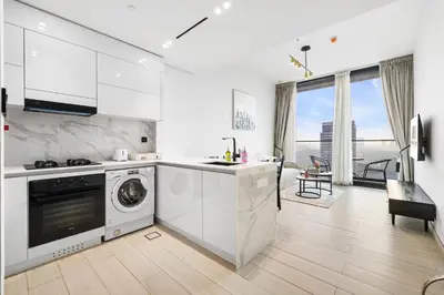 a white kitchen with a washer and dryer at BLVD Luxe Stay with Pool Heart of JVC in Dubai