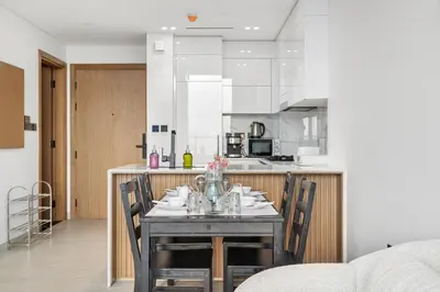 a dining room table with chairs and a kitchen at BLVD Luxe Stay with Pool Heart of JVC in Dubai