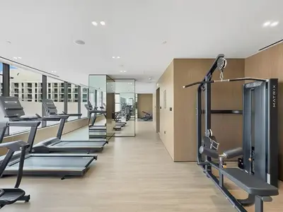 a gym with rows of tread machines and mirrors at BLVD Luxe Stay with Pool Heart of JVC in Dubai