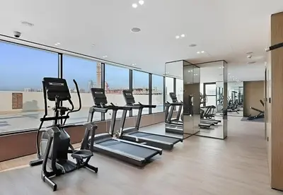 a gym with cardio equipment in a building with windows at BLVD Luxe Stay with Pool Heart of JVC in Dubai