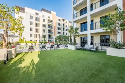 a large lawn with chairs and tables in front of a building at Seafront 2BR, Within Walking Distance to La Mer Beach, Short Drive Away from Mercato Mall, La Sirene Building 2, La Mer by Deluxe Holiday Homes in Dubai