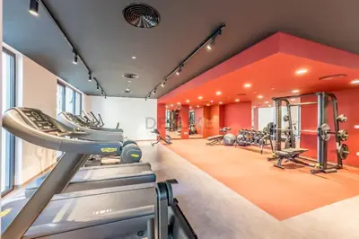 an orange gym with treadmills and ellipticals at Seafront 2BR, Within Walking Distance to La Mer Beach, Short Drive Away from Mercato Mall, La Sirene Building 2, La Mer by Deluxe Holiday Homes in Dubai