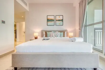 a bedroom with a large white bed with two lamps at Modern 1BR Retreat at Al Khail Heights, Al Quoz by Deluxe Holiday Homes in Dubai