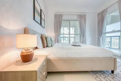 a bedroom with a bed and a lamp on a table at Modern 1BR Retreat at Al Khail Heights, Al Quoz by Deluxe Holiday Homes in Dubai