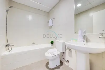 a white bathroom with a sink and a toilet and a tub at Modern 1BR Retreat at Al Khail Heights, Al Quoz by Deluxe Holiday Homes in Dubai