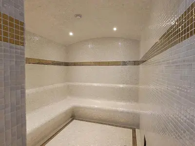 a bathroom with a walk in shower with white tiles at Miracle Luxury Studio in Dubai