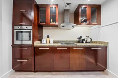 a kitchen with wooden cabinets and a microwave at Prime Dubai Marina Spot - Beach, Dining and leisure in Dubai
