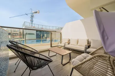 a balcony with chairs and a couch and a table at Private Pool Stylish 1BR Arjan in Dubai