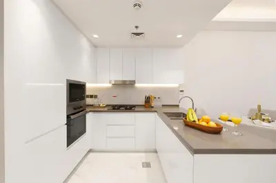 a white kitchen with a bowl of fruit on the counter at Private Pool Stylish 1BR Arjan in Dubai