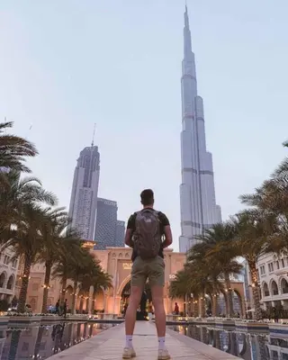 a man with a backpack standing in front of the burj at Luxury Stay - Walk to Dubai Mall & Burj Khalifa 21 in Dubai