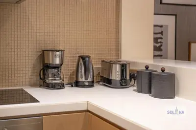 a kitchen counter with three coffeemakers on it at Lux One Bedroom at Damac paramount in Dubai