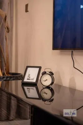 two clocks sitting on a glass table under a tv at Lux One Bedroom at Damac paramount in Dubai