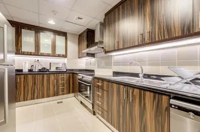 a large kitchen with wooden cabinets and a sink at JBR - spacious and neat 3br apt in Shams 1 in Dubai