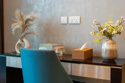 a desk with a blue chair and a vase of flowers at Luxury 2 Bedroom Apartment DAMAC Uppercrest Downtown Near Dubai Mall in Dubai