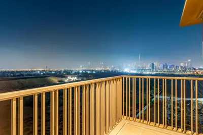 a balcony with a view of a city at night at Luxurious 1BR Retreat in MAG City Dubai in Dubai