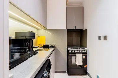 a kitchen with white cabinets and a stove top oven at Luxurious 1BR Retreat in MAG City Dubai in Dubai