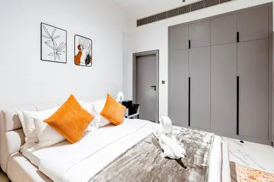 a bedroom with a large white bed with orange pillows at Luxurious 1BR Retreat in MAG City Dubai in Dubai