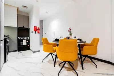 a dining room with a table and yellow chairs at Luxurious 1BR Retreat in MAG City Dubai in Dubai
