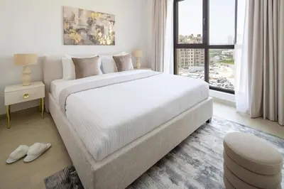 a white bedroom with a large bed and a window at Frank Porter - Jadeel 3 in Dubai