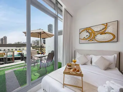 a bedroom with a bed and a balcony with a table at Livin' Holidays - Studio - Stylish flat in JVC in Dubai