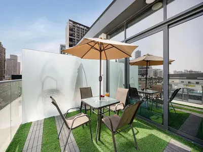 a table and chairs with an umbrella on a balcony at Livin' Holidays - Studio - Stylish flat in JVC in Dubai