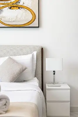 a bedroom with a bed and a nightstand with a lamp at Livin' Holidays - Studio - Stylish flat in JVC in Dubai