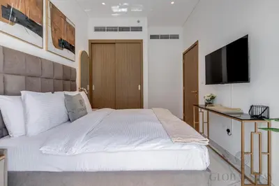 a bedroom with a large white bed and a flat screen tv at GlobalStay Azizi Riviera 67 Apartments Dubai in Dubai