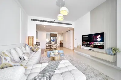 a living room with a white couch and a tv at Luxury 2BR Beach Isle With Palm Views and Beach Access in Dubai