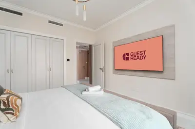 a white bedroom with a bed and a painting on the wall at GuestReady - 2BR | Downtown Bliss with Burj View in Dubai