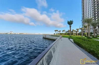 a walkway next to a body of water with palm trees at Premium 1BR with Panoramic Views Creek Harbour Steps from Creek Harbour Walk in Dubai