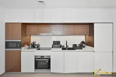 a kitchen with white appliances and wooden cabinets at Premium 1BR with Panoramic Views Creek Harbour Steps from Creek Harbour Walk in Dubai