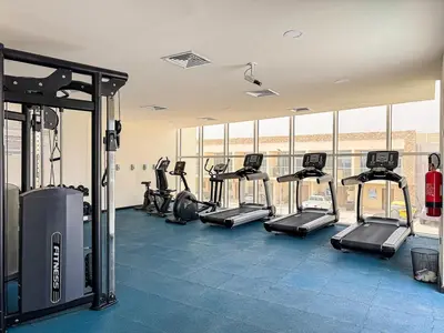 a gym with a bunch of treadmills and ellipticals at Stylish 1BR Villa near Global Village and Golf Clubs in Dubai