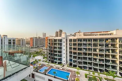 a large white building with a swimming pool in a city at Livin' Holidays - Studio - Stylish Stay in Azizi in Dubai