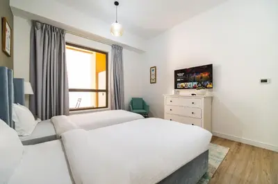 a bedroom with two beds and a couch at SettlerHomes - Stunning JBR 2BR Just 5mins To The Beach in Dubai