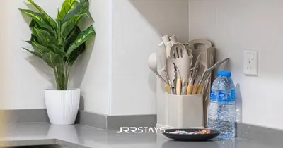 a counter with a vase with scissors and a bottle of water at Stylish Luxury 1BR - Modern Design - JVC in Dubai