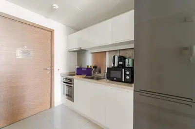 a white kitchen with a sink and a microwave at Silkhaus Chic Studio in Downtown at Claren Tower in Dubai