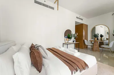 a white bedroom with a white couch and a living room at Silkhaus Chic Studio in Downtown at Claren Tower in Dubai