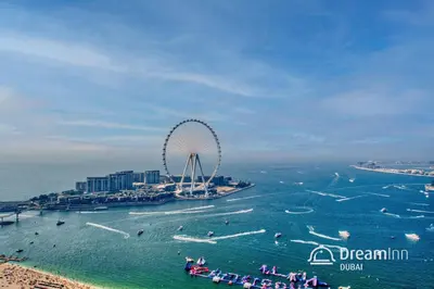a ferris wheel in the water next to a beach at Dream Inn - Timeless Arabic-Inspired Penthouse with Private Pool and Sweeping Ain Dubai Views in Dubai