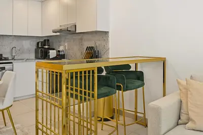 a kitchen with a yellow counter with green bar stools at Luxury 1BD Stay in Lamtara 2, Near Jumeirah Burj in Dubai