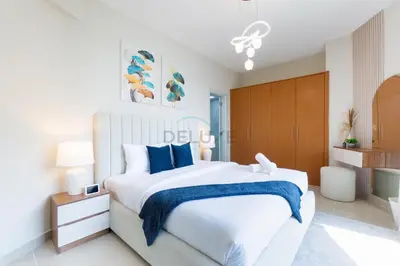 a white bedroom with a large bed with blue pillows at Balcony Offering Captivating Lake Views 1BR, Just a Hop from the Golf Course, Lakeside B, Dubai Production City by Deluxe Holiday Homes in Dubai