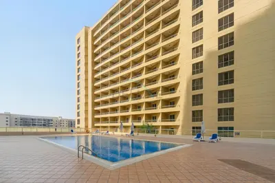 a large building with a swimming pool in front of it at Balcony Offering Captivating Lake Views 1BR, Just a Hop from the Golf Course, Lakeside B, Dubai Production City by Deluxe Holiday Homes in Dubai