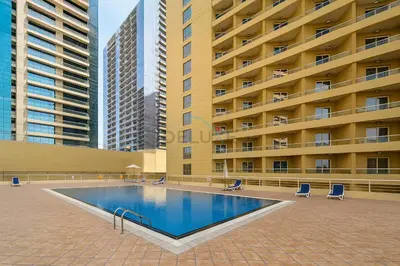 a swimming pool in front of a large building at Balcony Offering Captivating Lake Views 1BR, Just a Hop from the Golf Course, Lakeside B, Dubai Production City by Deluxe Holiday Homes in Dubai