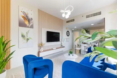 a living room with blue chairs and a tv at Balcony Offering Captivating Lake Views 1BR, Just a Hop from the Golf Course, Lakeside B, Dubai Production City by Deluxe Holiday Homes in Dubai