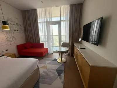 a hotel room with a bed and a red chair at Luxery Hotel Apartment l Novotel Residence l JVT in Dubai